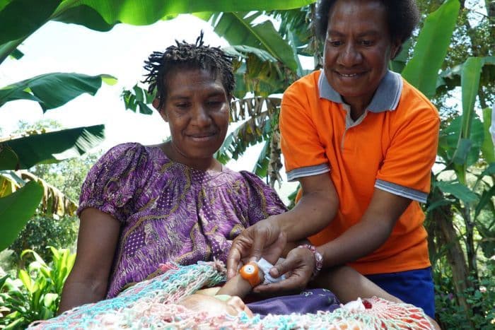 A community health worker in Papua New Guinea shows a mother how to use TempWatch