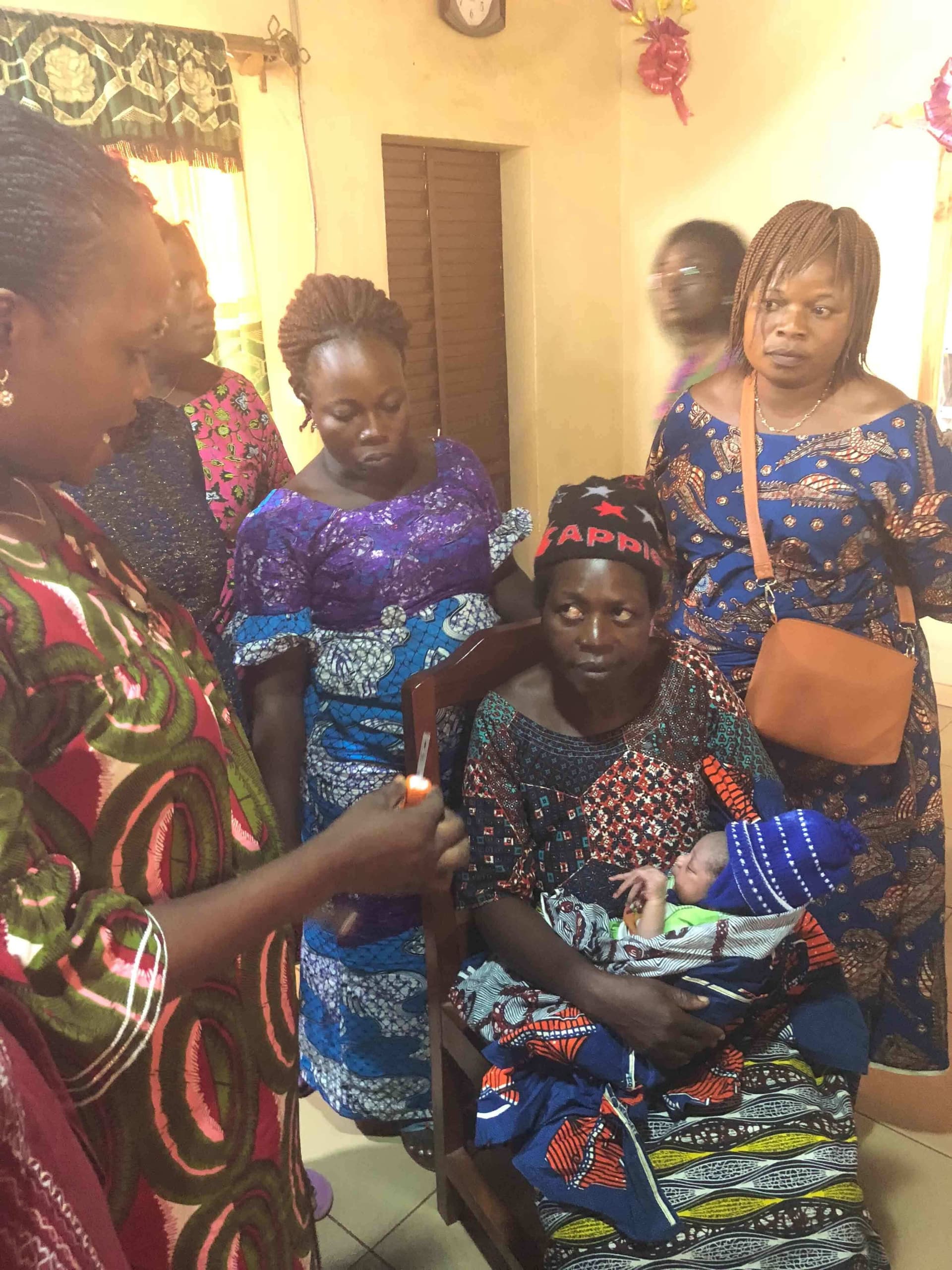 A health worker in Benin fits a mother's newborn with a BEMPU TempWatch bracelet