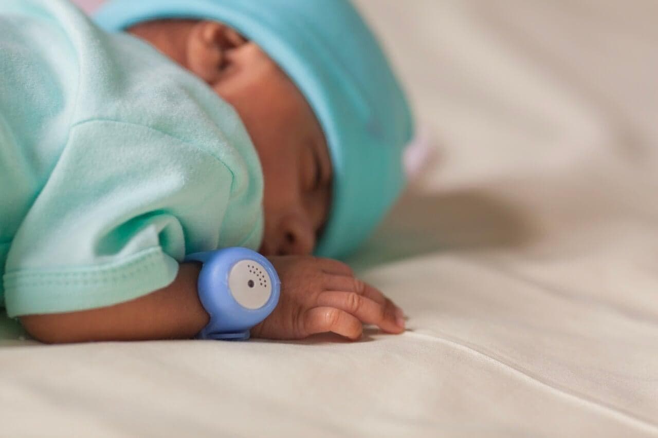 A mother gently caring for her newborn wearing a TempWatch
